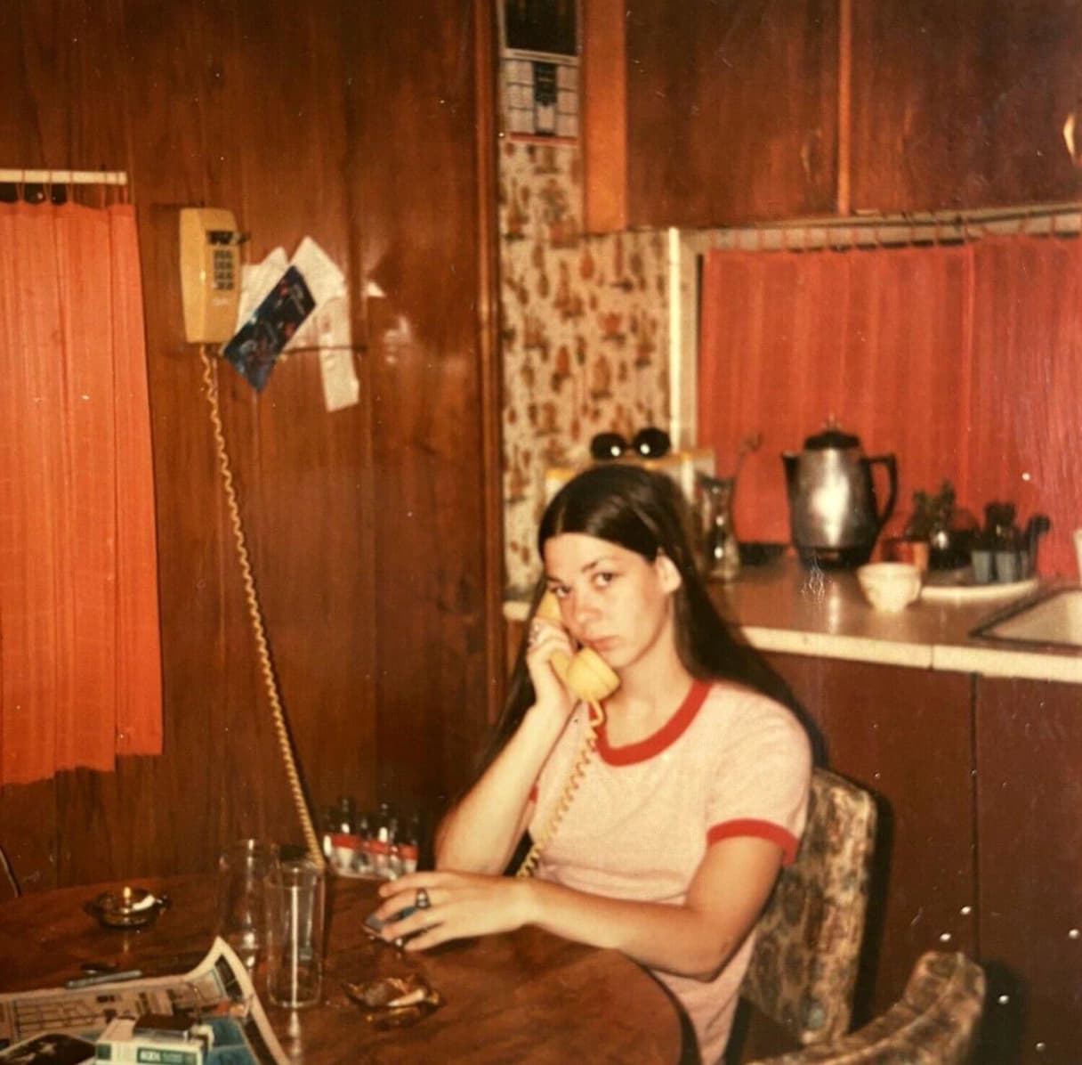 A woman makes a phone call on a landline telephone, circa 1970. 